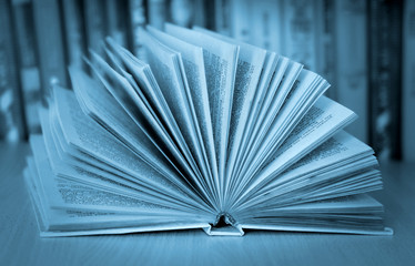 Open book on the background of books (cyan tones)