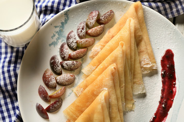 Sticker - Plate with tasty thin pancakes and plums on table, closeup