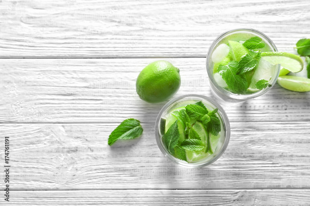 Cold fresh mojito with mint and lime slices in glasses on wooden background