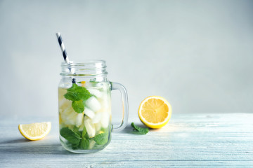Fototapete - Cold fresh mojito with mint and lemon slices in mason jar on wooden table