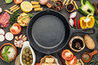 Italian food cooking ingredients on dark stone background with  cast iron pan flat lay and copy space.