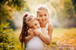 © svetabezu - Childhood, family, friendship and people concept - two happy kids sisters hugging outdoors.