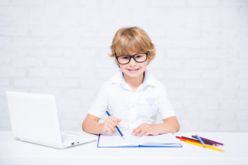 Sticker - happy little school boy in glasses doing homework with laptop