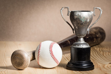 still life photography : baseball equipment and old trophy on wood table against space of brown shading background