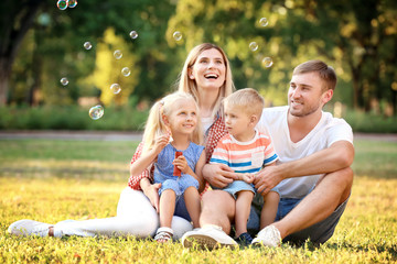 Sticker - Happy family blowing soap bubbles in park on sunny day