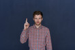 © Anatoliy Karlyuk - I have an idea. Waist up shot of handsome positive young man with trimmed beard smiling, raising hand and pointing index finger up as sign that some brightly idea or thought crossed his mind