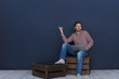 © Anatoliy Karlyuk - Bearded young man of creative occupation sitting on wooden pallet with portable computer on his lap and pointing finger at blank copy space wall for your text, information or advertising content