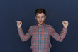 © Anatoliy Karlyuk - Picture of attractive young bearded male employee dressed in checkered shirt raising hands while stretching arms after productive working day at office, feeling tired but happy with great results