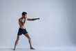 © Anatoliy Karlyuk - Full length shot of muscular athletic young Caucasian kickboxer training in studio, punching air, preparing for fight, wearing black shorts and no shoes. People, sports, boxing and fighting
