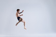 © Anatoliy Karlyuk - Freeze action shot of flying shirtless and barefooted young male boxer wearing trunks jumping high against blank grey studio wall background with copy space for your advertising information