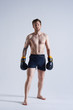 © Anatoliy Karlyuk - Full lenght shot of good looking barefooted young male model with thick beard and perfect muscular body wearing boxing gloves and trunks posing in studio during photoshooting for sports magazine