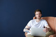 © Anatoliy Karlyuk - Trendy looking young European redhead male graphic designer with trimmed beard working on web site design, sitting in armchair with portable computer at blank wall with copy space for your text