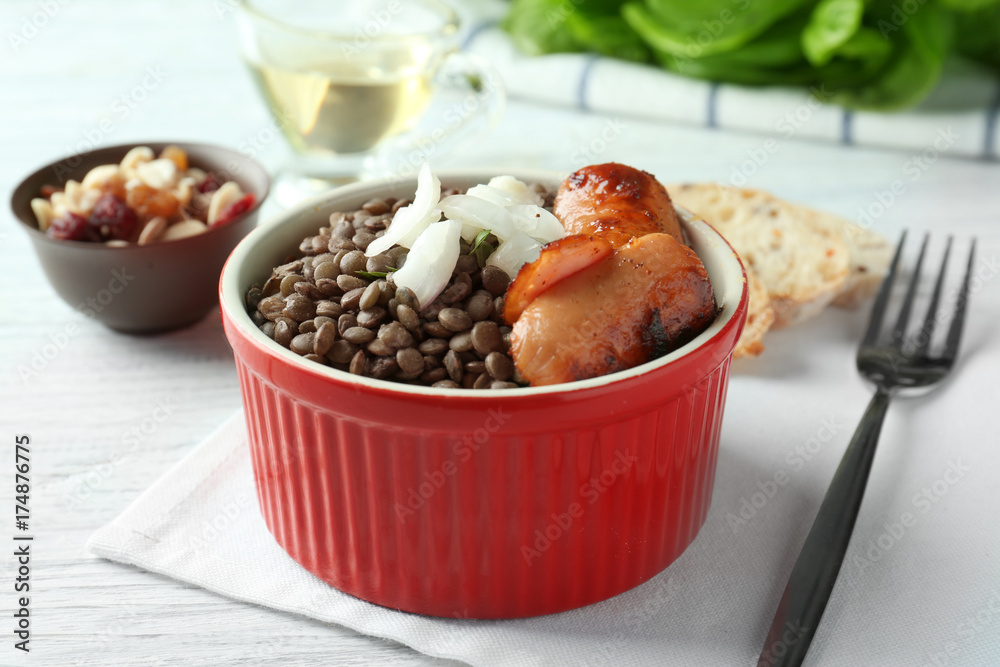 Ramekin with black lentils and sausages on table