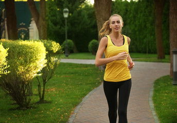 Wall Mural - Sporty young woman running in park