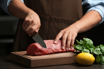 Wall Mural - Chef cutting fresh raw meat on wooden board