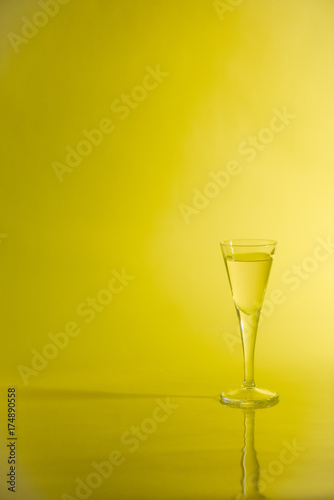 Fotografie, Obraz Yellow liquid in aperitif glass on yellow background.