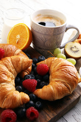 Delicious breakfast with fresh croissants and ripe berries on ta