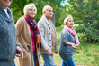 © Seventyfour - Elderly friends wearing knitted sweaters enjoying fresh air and picturesque view while walking along park alley