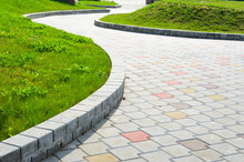 Curved Garden Stone Path Pesperctive View. Multicolored Sidewalk Tile Road Background
