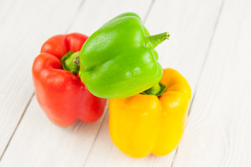 Heap of red yellow and green fresh whole raw pepper on old white rustic planks