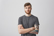 © Cookie Studio - Portrait of beautiful young man with ginger beard and tattooed hand looking in camera with gentle smile and calm expression.