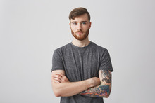 Portrait Of Beautiful Young Man With Ginger Beard And Tattooed Hand Looking In Camera With Gentle Smile And Calm Expression.
