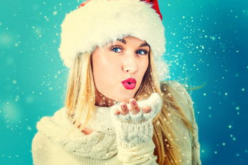 Sticker - Happy young woman with Santa hat blowing snow