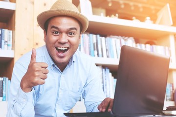 young man  hand thumb up while using computer laptop happily.