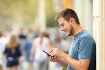 Profile of a happy guy texting on a smart phone