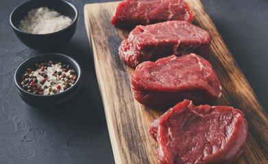 Sticker - Raw beef filet mignon steaks with spices on wooden board at blac