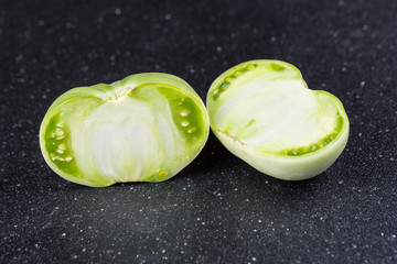 Fresh sliced green tomatoes on a black background