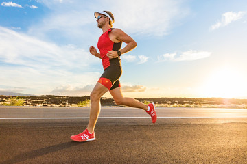 triathlon - triathlete man running in triathlon suit training for ironman race. male runner exercisi