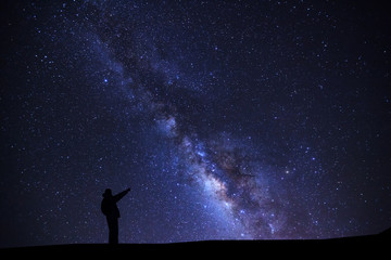 Wall Mural - a man is standing pointing on a bright star with milky way galaxy and space dust in the universe