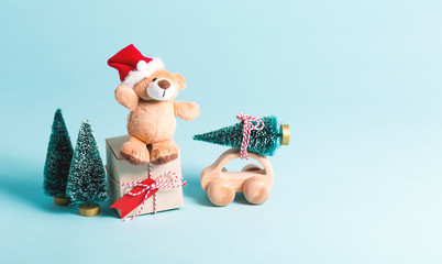 Sticker - Small teddy bear in a Santa hat with a present box and Christmas trees