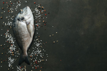 Delicious fresh fish with spices on dark vintage background. Top view