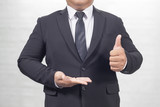 Fototapeta Pomosty - businessman in a suit opening palm hands and Thumbs Up