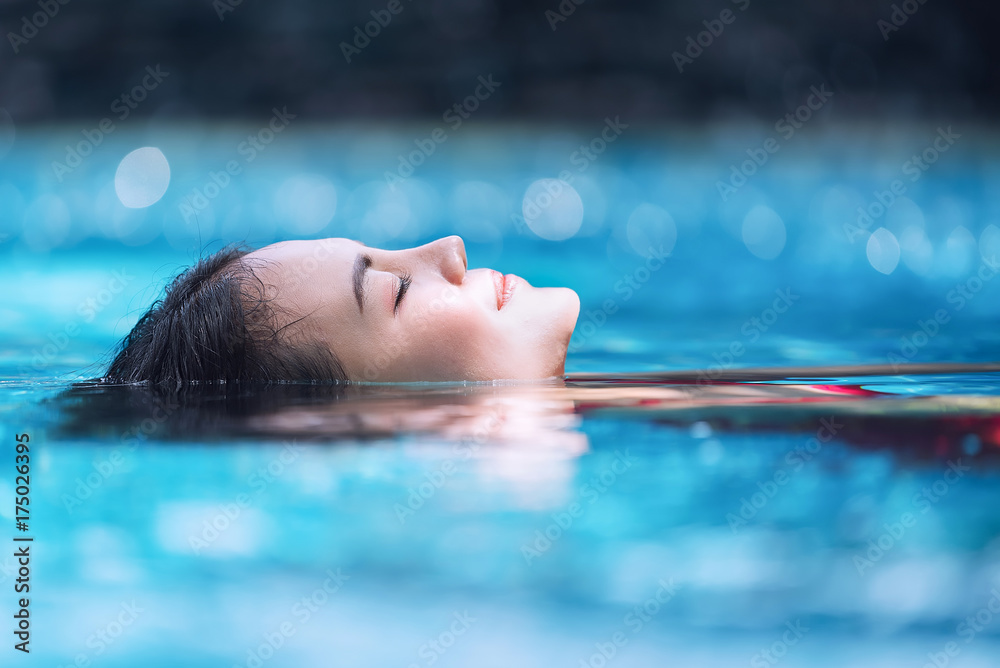 Young asian woman relaxing in swimming pool at spa resort. - obrazy, fototapety, plakaty 