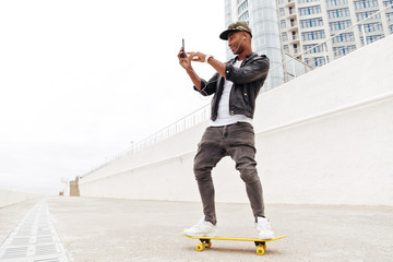 Poster - Young african man using phone and listening music.