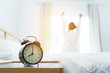 Closeup alarm clock, Young asian woman wake up in the moring and stiing on bed at mirror door side relaxing in holiday with sunlight