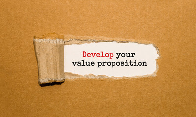 Poster - the text develop your value proposition appearing behind torn brown paper