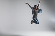 Playful young woman wearing casual jumping over grey background. Look at camera and screaming.