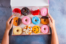 Hand Holding Box With Sweet Doughnuts On Gray Stone Background