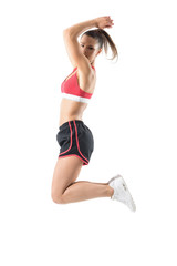 Wall Mural - Side view of fit active sporty woman jumping in mid air looking back over shoulder. Full body length portrait isolated on white studio background.