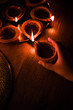 Happy diwali - Hand holding or lighting or arranging diwali diya or clay lamp in brass plate, selective focus