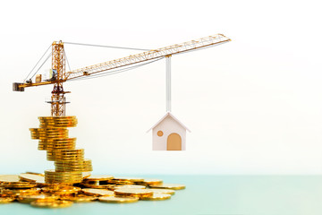 Stacking gold coins with increase and tower crane and hoist brake solutions with build new house in the office, saving money and loan for construction real estate and home concept.