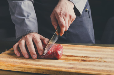 Sticker - Chef cutting filet mignon on wooden board at restaurant kitchen