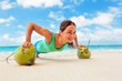 © Tropical studio - Active woman doing fitness exercise plank on coconut to keep fit and health. Beach surf background. Healthy lifestyle, morning workout, sport activity on summer family vacation in tropical island.