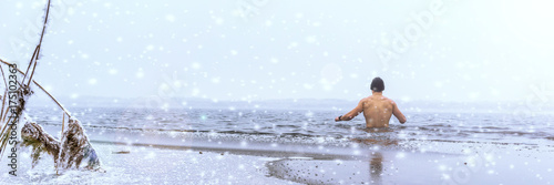 Zdjęcie XXL Mężczyzna kąpanie się w lodzie w zimie, panorama z opadem śniegu