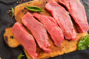 Overhead of beef steaks on wooden cutting board. Slices of beef. Beef tenderloin. Cooking dinner.