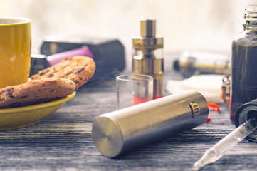 Still life with electronic cigarette with botle and coffe on the wooden background